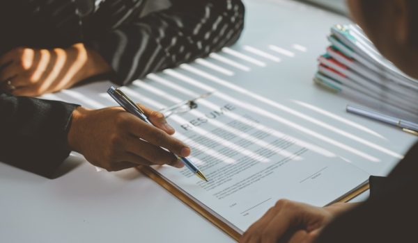 Human resources manager pointing at a resume with a pen while conducting an interview with a candidate for a job position in a modern office setting
